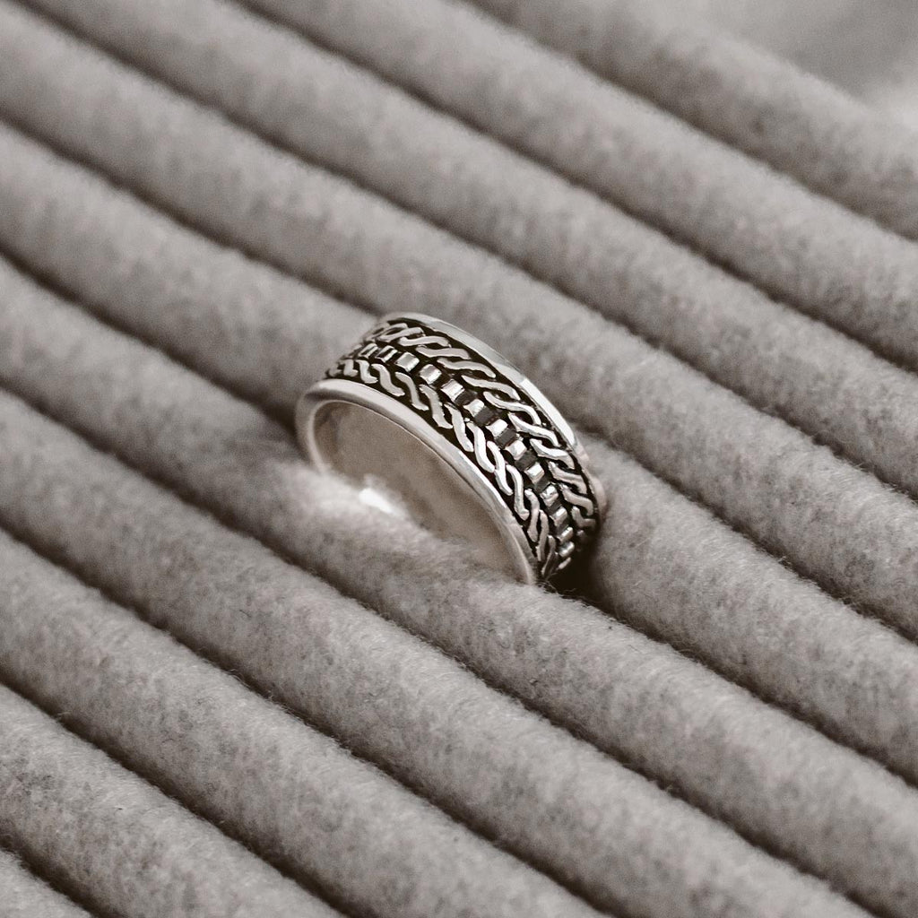 Ein silberner Ring, der auf einer grauen Decke liegt.