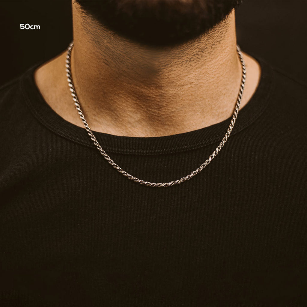 A close up of a man wearing a chain necklace.