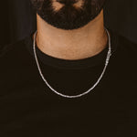 Man wearing a sterling silver Ramsi byzantine chain from Ninetwofive with a black collarless T-shirt.