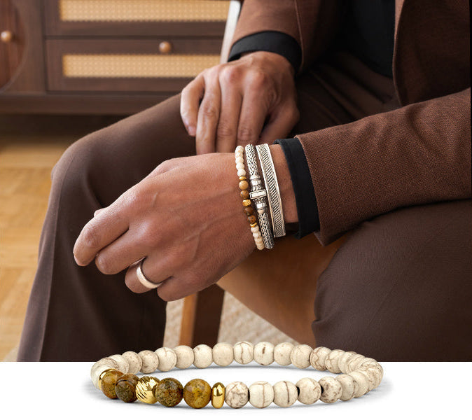 closeup shot of a gentleman wearing a silver bracelet a silver bangle and a free beaded bracelet