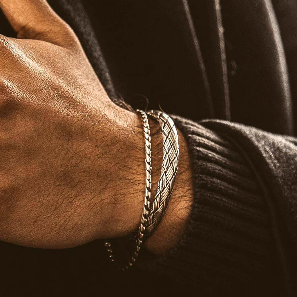 A person wearing a bracelet with a chain on it.