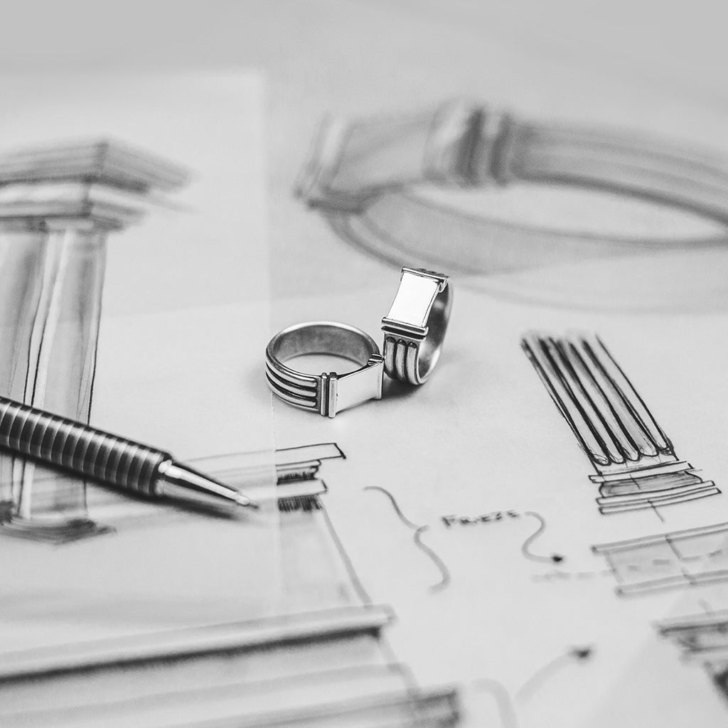 A black and white photo of a wedding ring on a piece of paper.