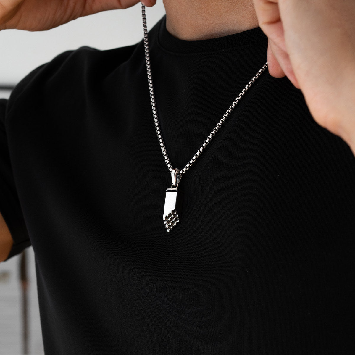 Model wears Muqarnas mens chain pendant with black diamonds by Ninetwofive, styled over black shirt front view.