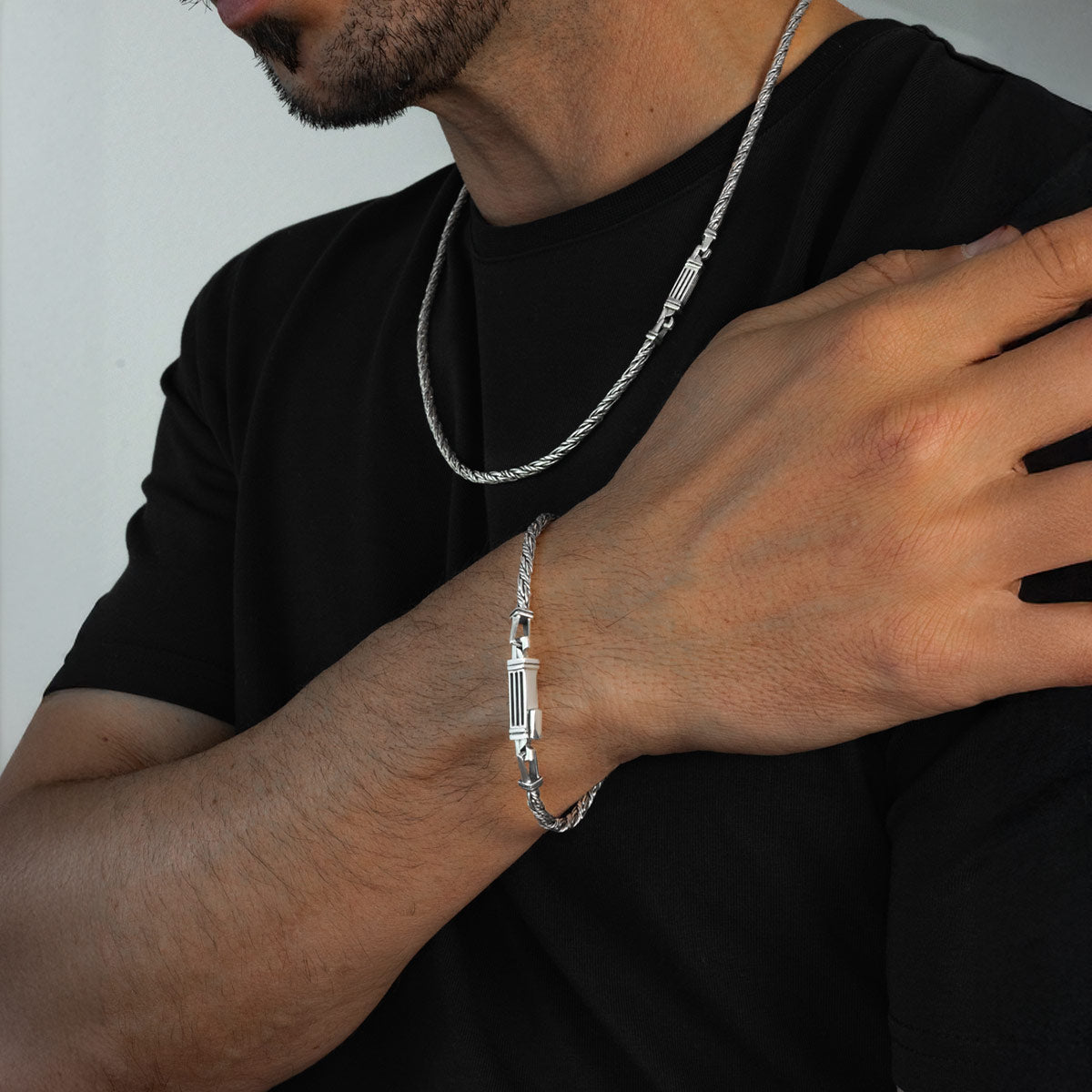 Man draagt Nadir 925 touwketting herenarmband om zijn pols en zilveren ketting van Ninetwofive.