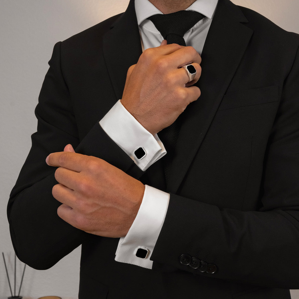Model in een zwart pak draagt Nael Black Onyx heren manchetknopen met zilveren ring van Ninetwofive.