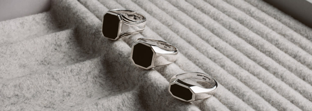 Three silver rings on a gray cloth.
