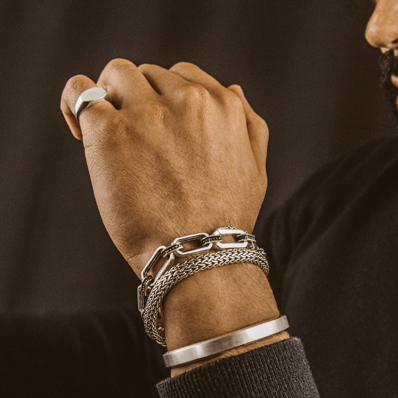 Een man die een CAqwas-armband voor heren draagt, gemaakt van 925 sterlingzilver, met zwarte steentjes en een manchet.