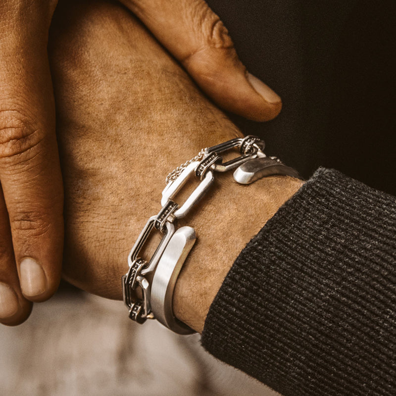 De man in de zwarte trui draagt de Aqwas-armband en-manchet van sterlingzilver.
