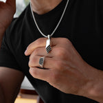 Das Model präsentiert die Herren-Halskette „Muqarnas“ und den Designer-Ring „Azhar“ von Ninetwofive Stil Ninetwofive Schwarzdiamant-Silber.