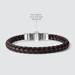 A dark brown braided leather bracelet with a silver-toned metal clasp, shown on a light gray background with an overlay text pointing to the clasp for personalization.
