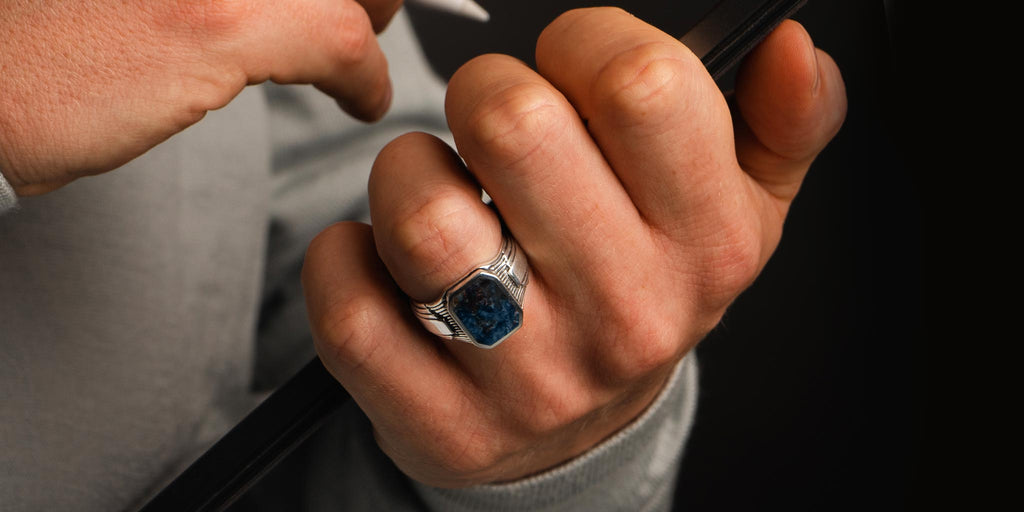 A hand holding a blue topaz ring.