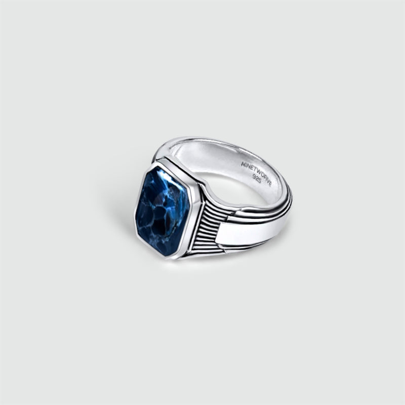Een Bariq heren zegelring, vervaardigd uit sterlingzilver en bezet met een blauwe topaas, voorzien van het gegraveerde 925- en Ninetwofive-keurmerk.
