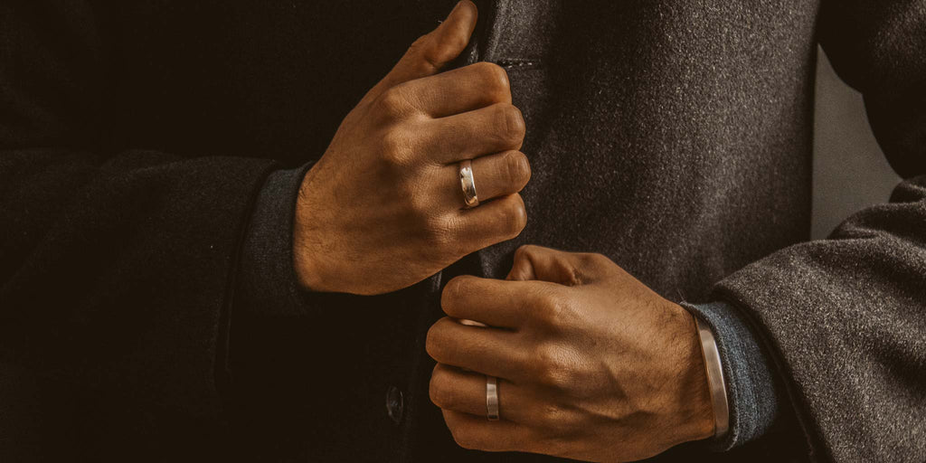 Ein Mann im Anzug steckt sich einen Ring an.