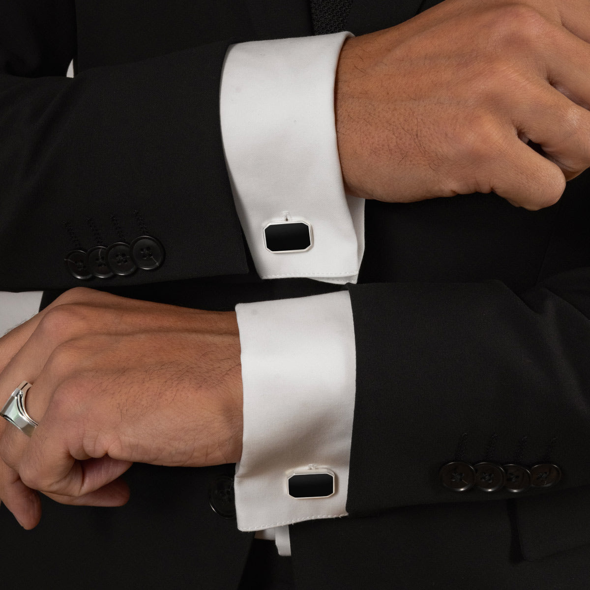 Model in zwart-wit pak draagt zwarte onyx manchetknopen van Rael met zilveren ring van Ninetwofive