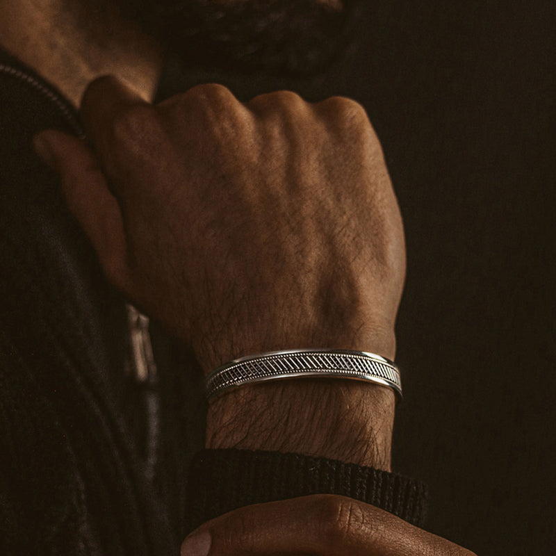 Een man die een Kaliq-armband voor heren van geoxideerd sterlingzilver draagt.