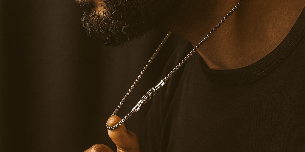 A man with a beard wearing a silver chain necklace.