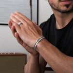 Homme portant des bagues en argent et de l'argent boîte bracelets en chaîne sur ses mains sur fond neutre