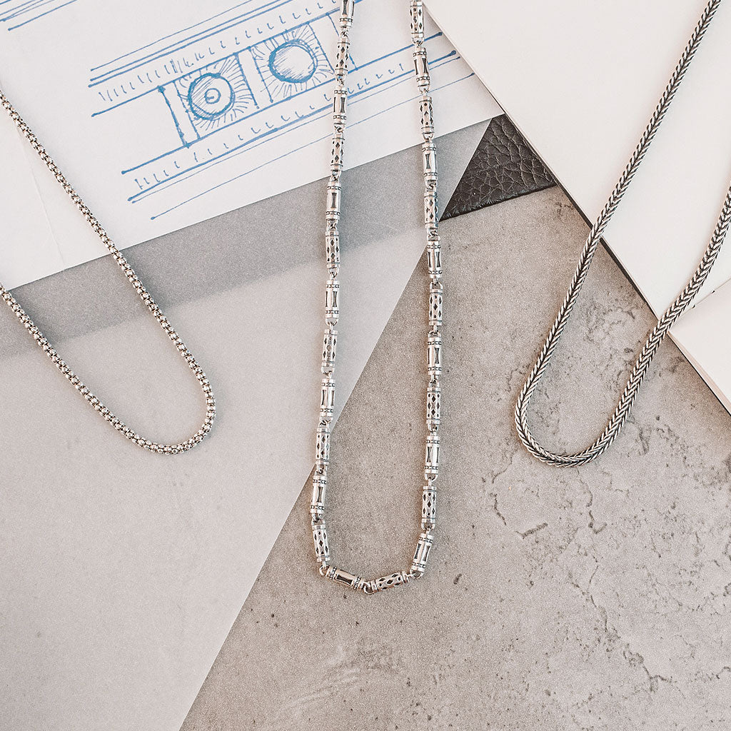 Rope, cavetto, box and link silver chain for men laying on top of a piece of paper. Ninetwofive