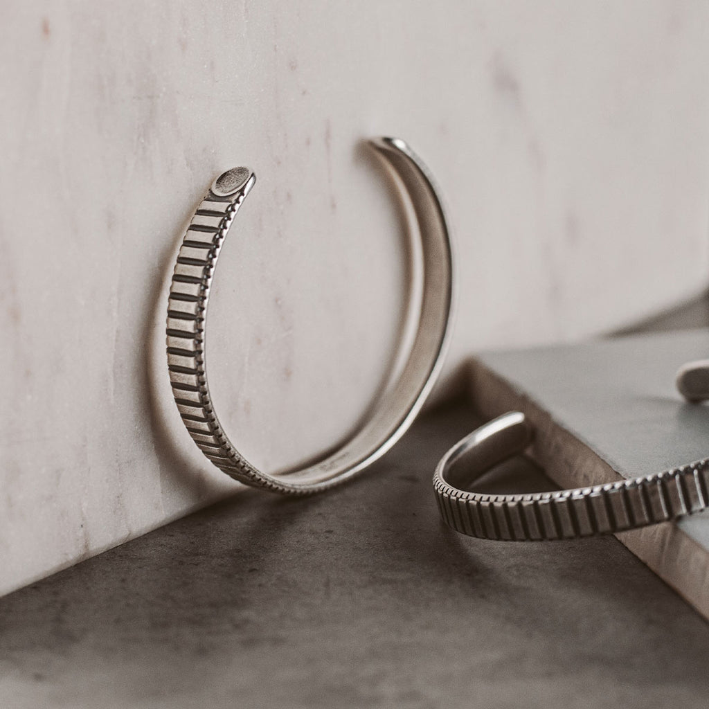 A pair of silver cuff bracelets on a table.