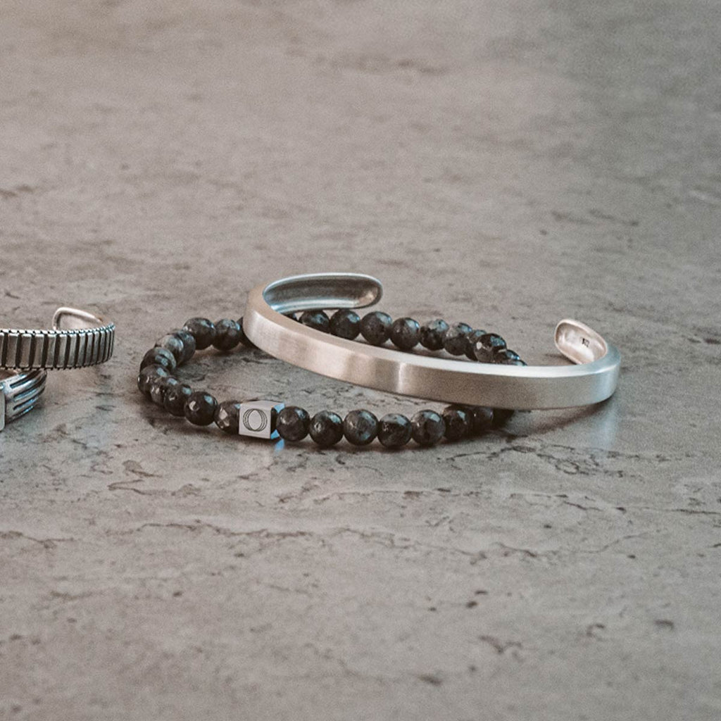A pair of bracelets with a black bead and a silver ring.