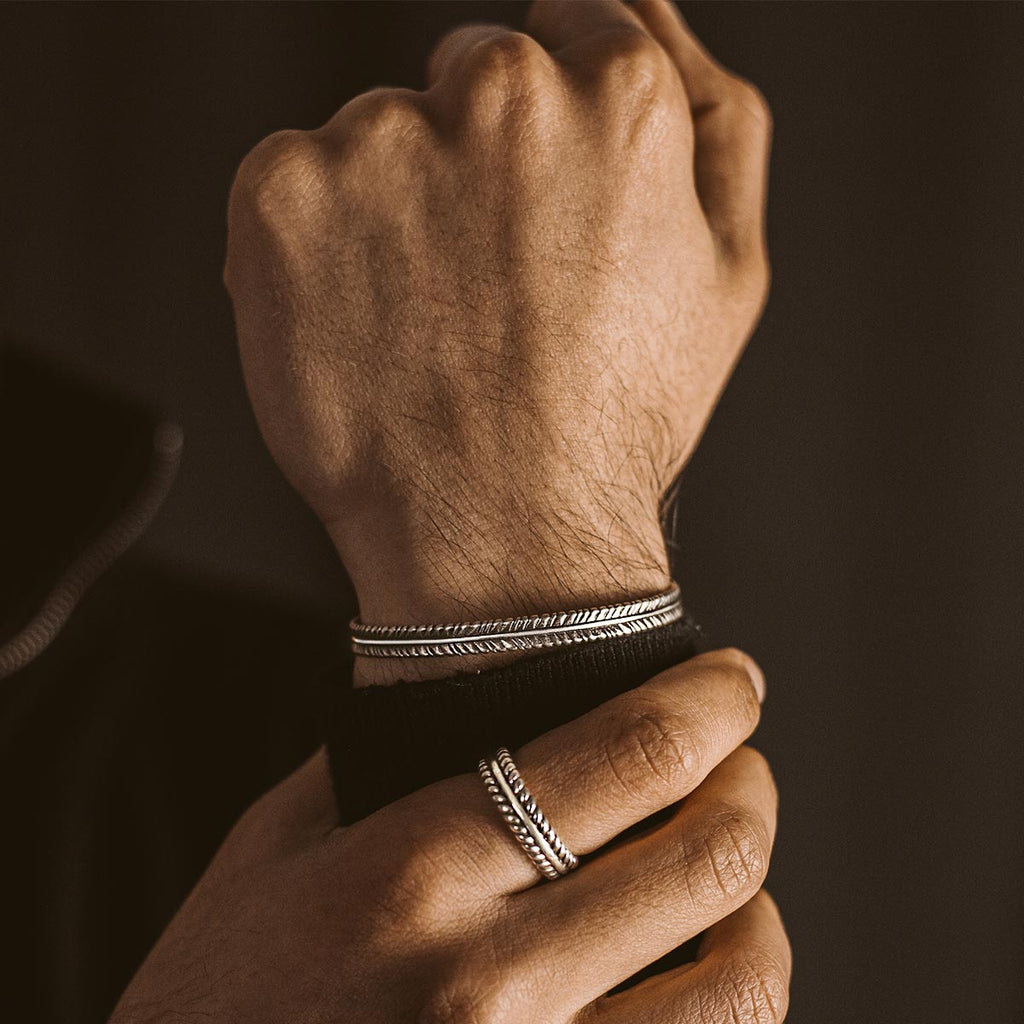 A man wearing a pair of silver bangles.