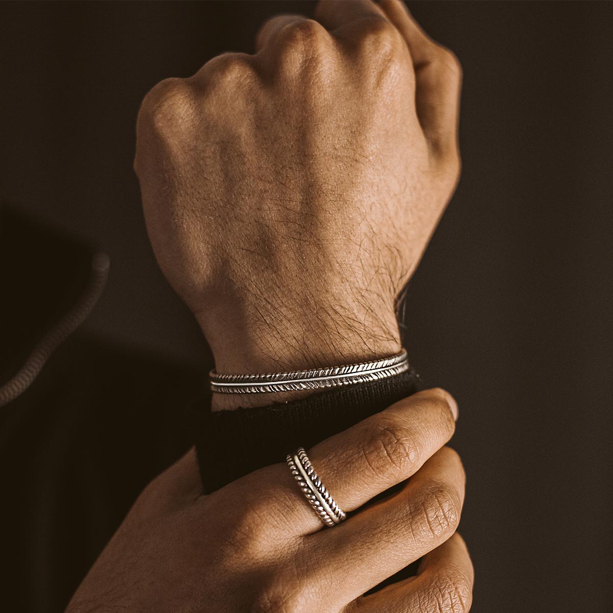 A man wearing a Zahir- cuff and Zahir Ring.
