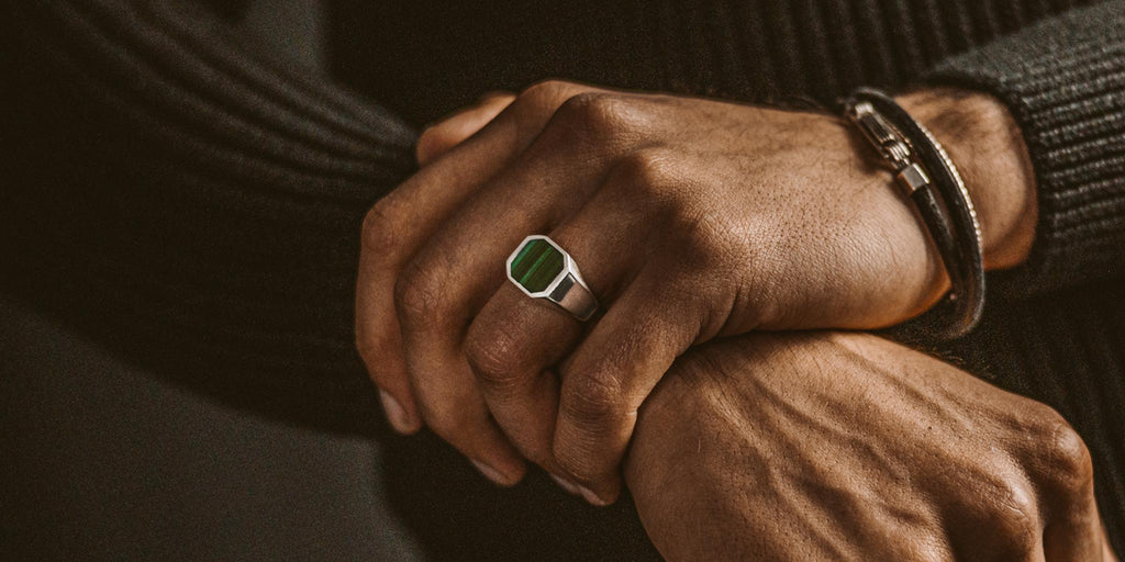 A man wearing a ring with a green stone.