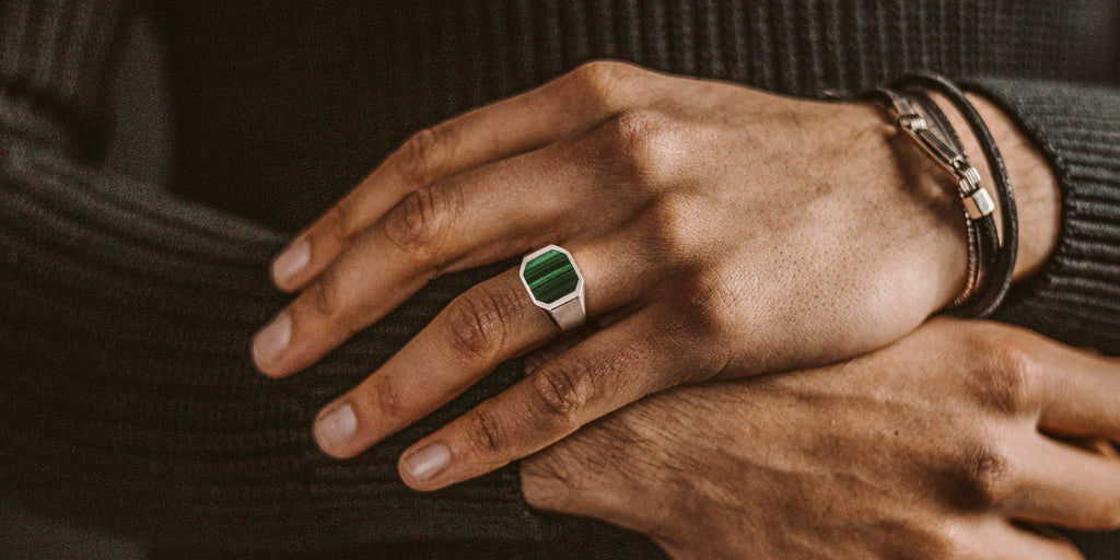 Ein Mann trägt einen Ring aus grünem Stein.