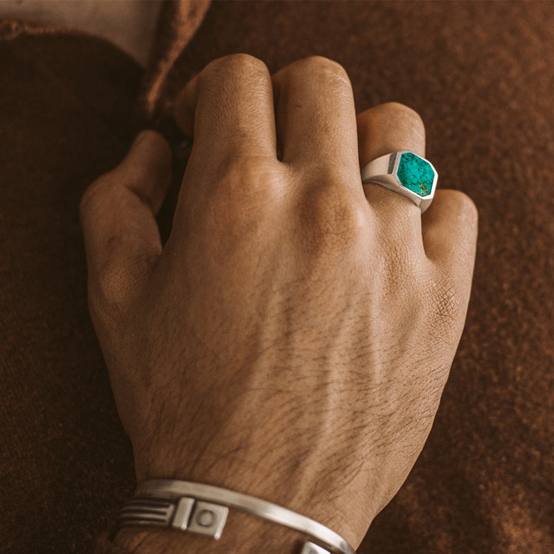 A man in brown shirt touching his buttons while wearing Nuri mens signet ring and silver bracelets by Ninetwofive. 