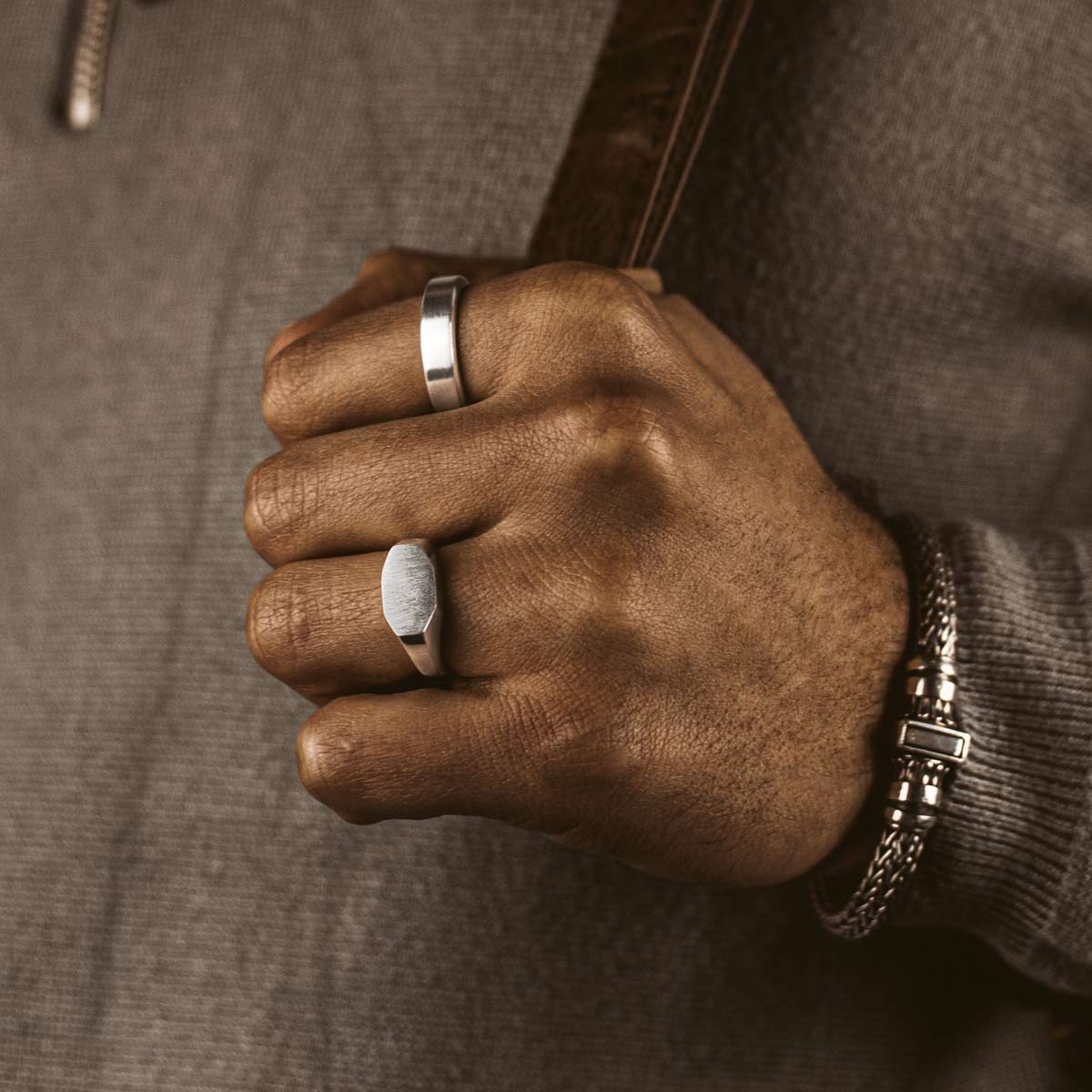 Model wearing silver signet ring and men’s bracelet from ninetwofive