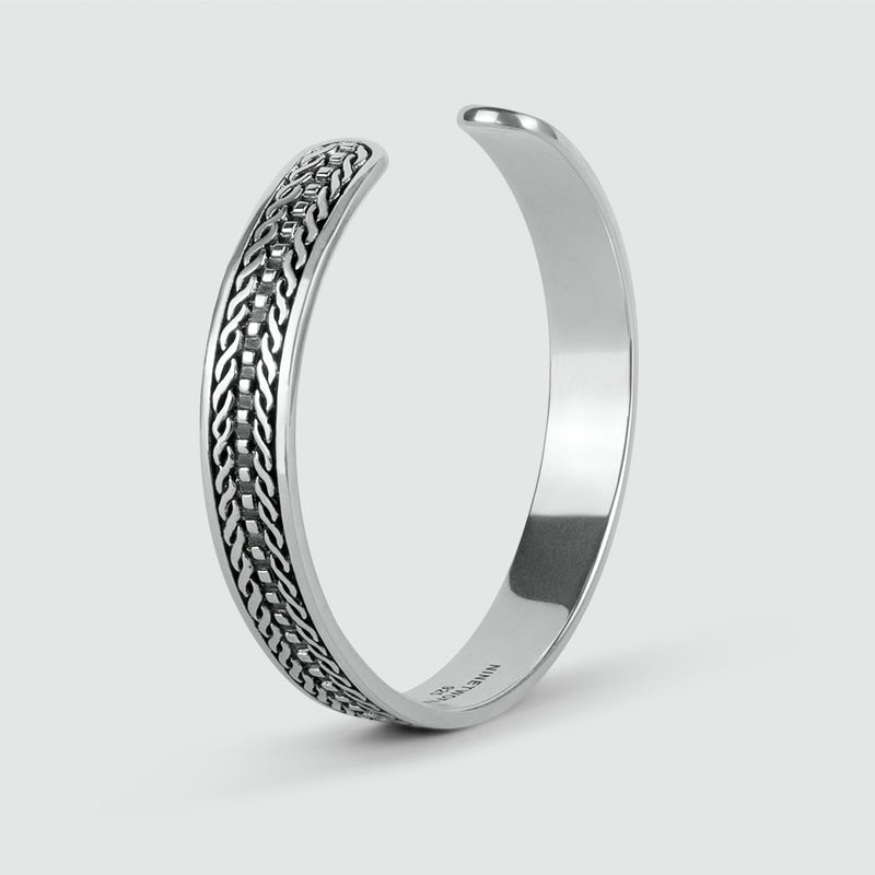 Hoekaanzicht van de Fariq geoxideerde 925 sterling zilveren heren cuff armband met gevlochten design.