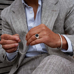 Model wearing Adil sterling silver black onyx men’s signet ring and holding mens bracelet from Ninetwofive.