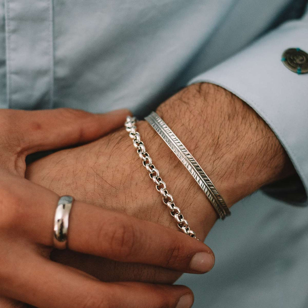 A man wearing a silver bracelet on his wrist.