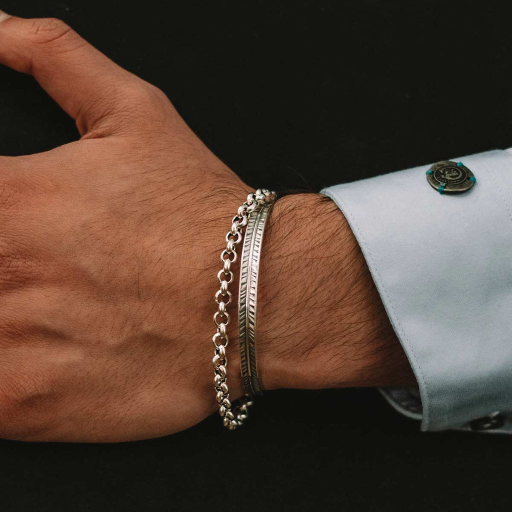 A man's hand with a silver bracelet on it.