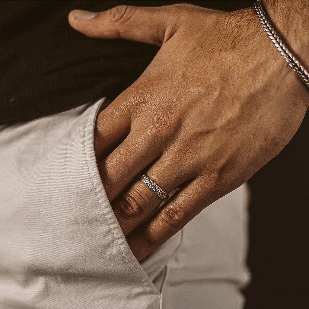 Een man houdt een zilveren ring in zijn zak.