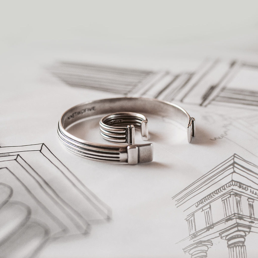 A silver cuff laying on top of a drawing.
