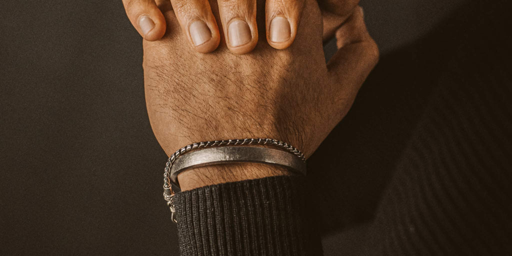 A man's hand wearing a bracelet.
