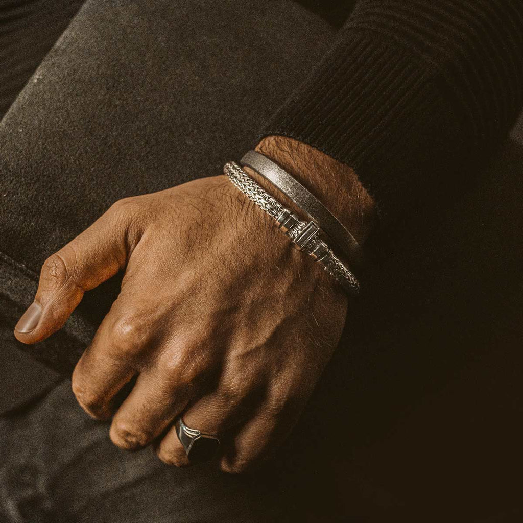 A hand holding a silver bracelet.