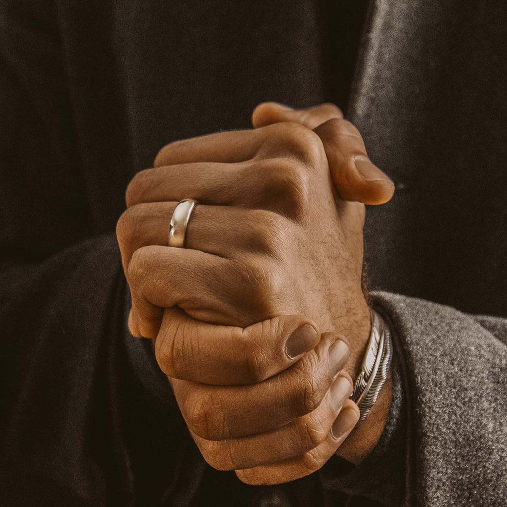 A man is holding his hands and wearing a wedding ring.
