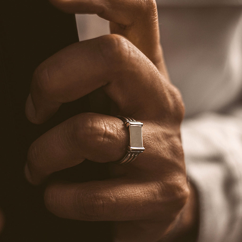 A hand holding a silver ring.