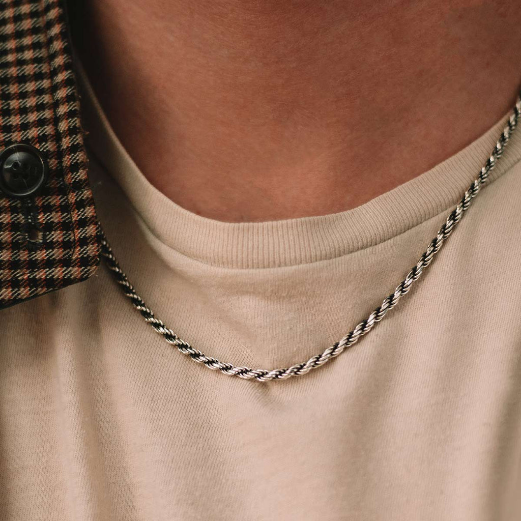 A close up of a man wearing a silver necklace.
