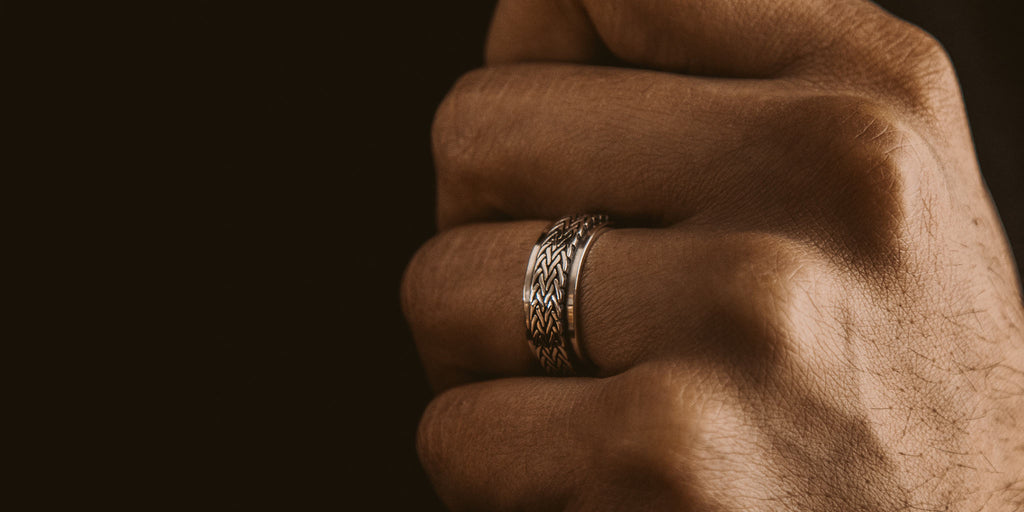 Een mannenhand met een zilveren ring eraan.
