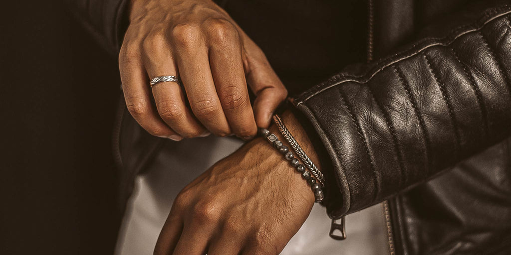 A person wearing a leather jacket with a ring on their hand.
