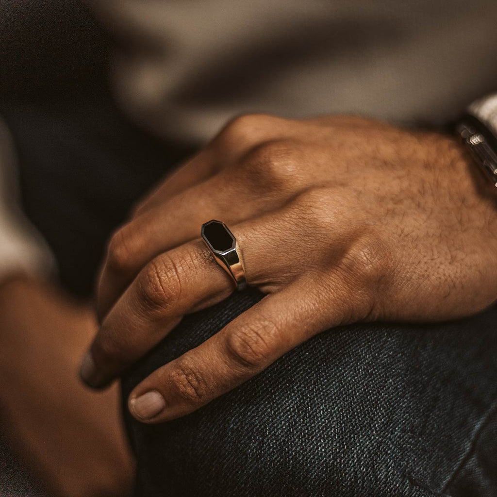 A man wearing a ring with a black stone on it.