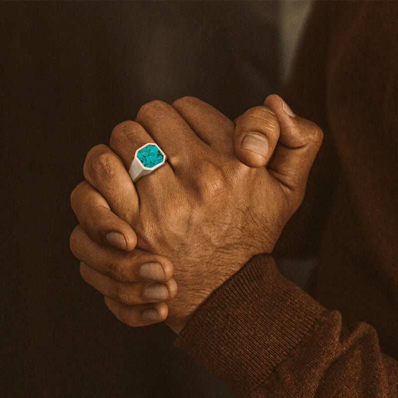 Man in brown sweater wears the Nuri sterling silver mens ring, holding his palms together, Ninetwofive.