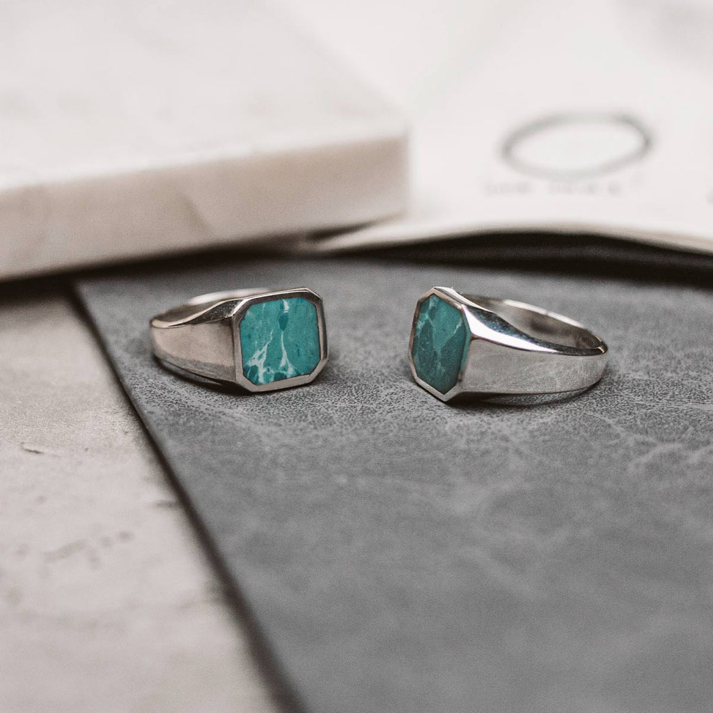 A pair of silver rings with a turquoise stone.