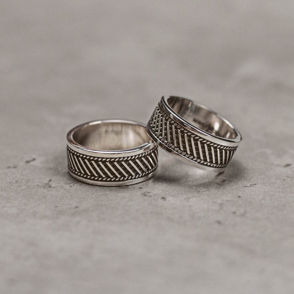 Zwei silberne Ringe mit einem Muster auf ihnen.