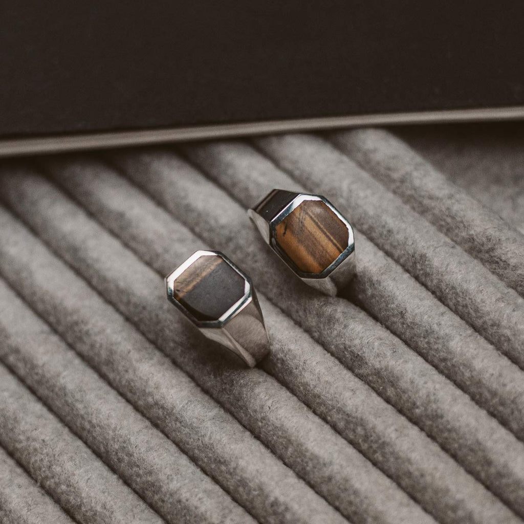 A pair of tiger eye signet rings on a background.