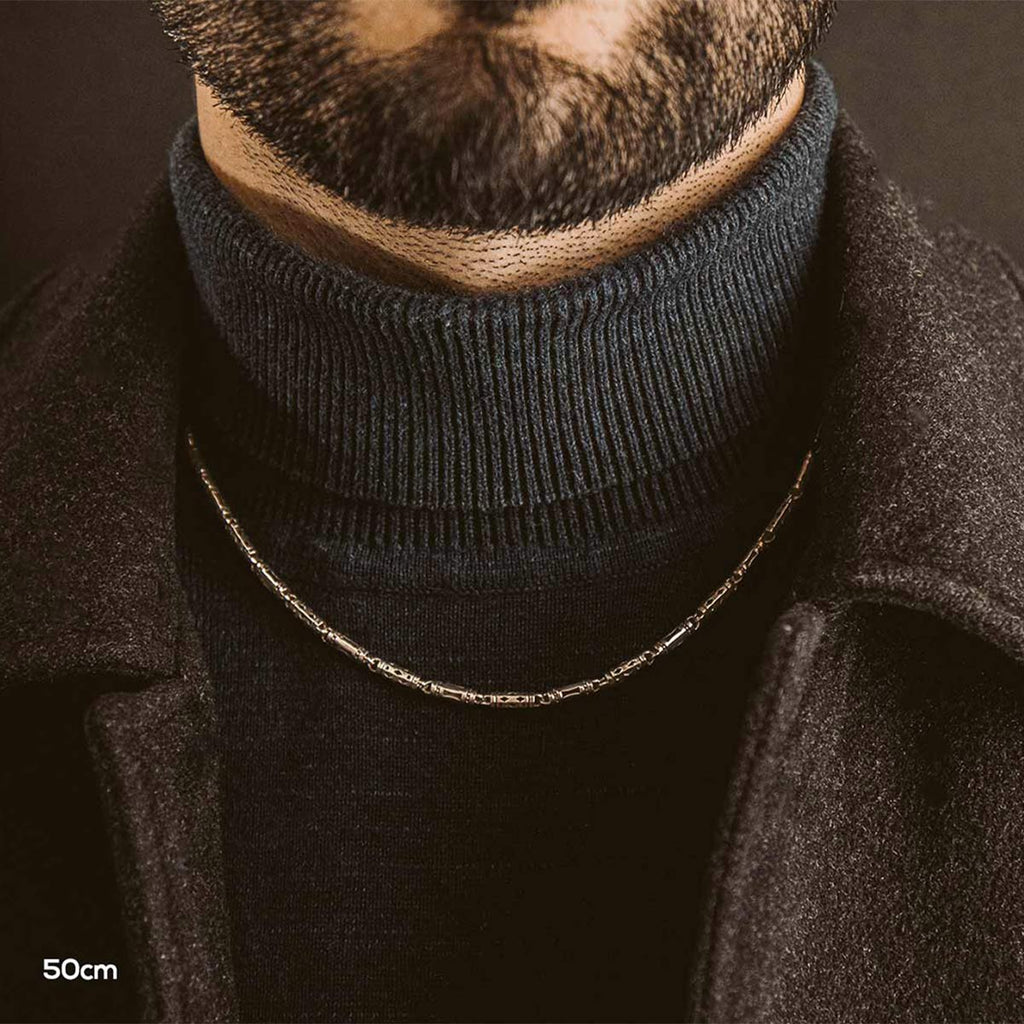 A man wearing a turtle neck necklace.