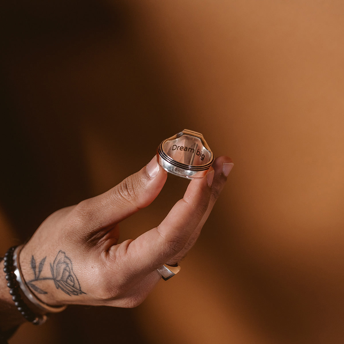 Bague Saint-Valentin pour homme tenue dans la main, accompagnée d'un bracelet à perles offert en cadeau.